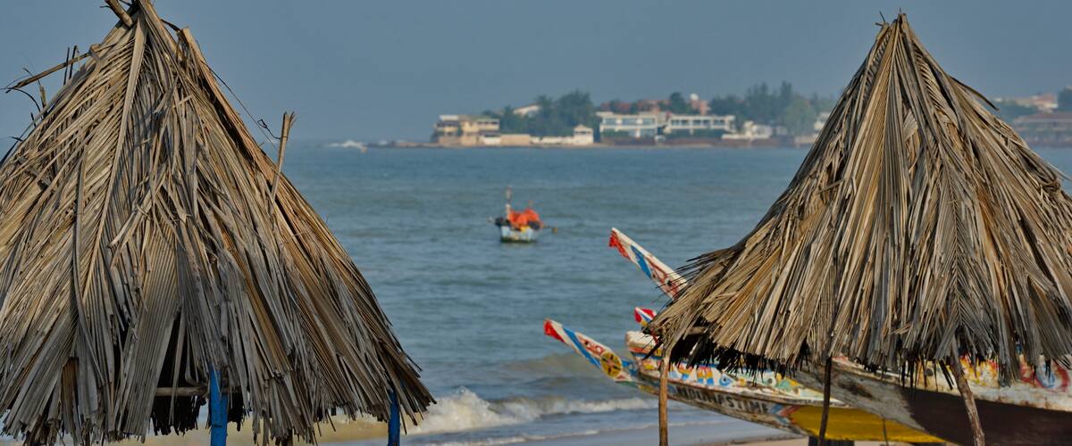 A beach with thatched umbrellas and a boat with colorful decorations.