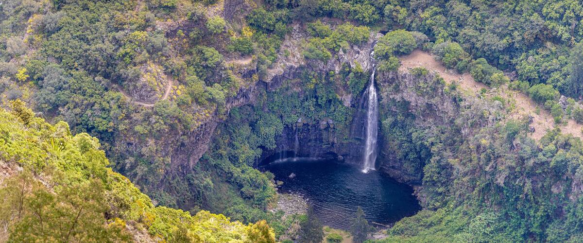 A waterfall cascading into a deep valley surrounded by dense forest.