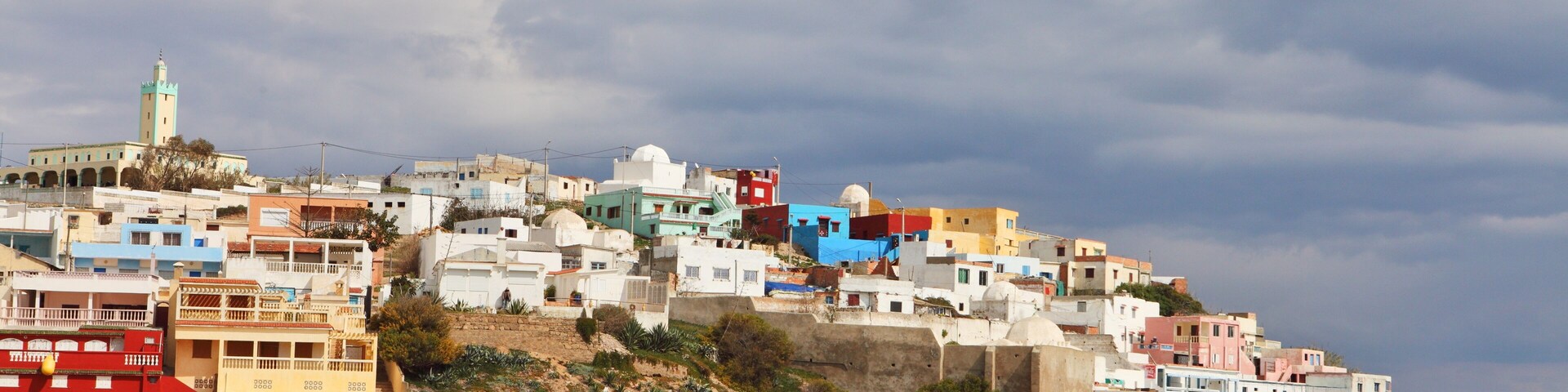 Un pueblo costero con edificios coloridos, una playa y un bote.