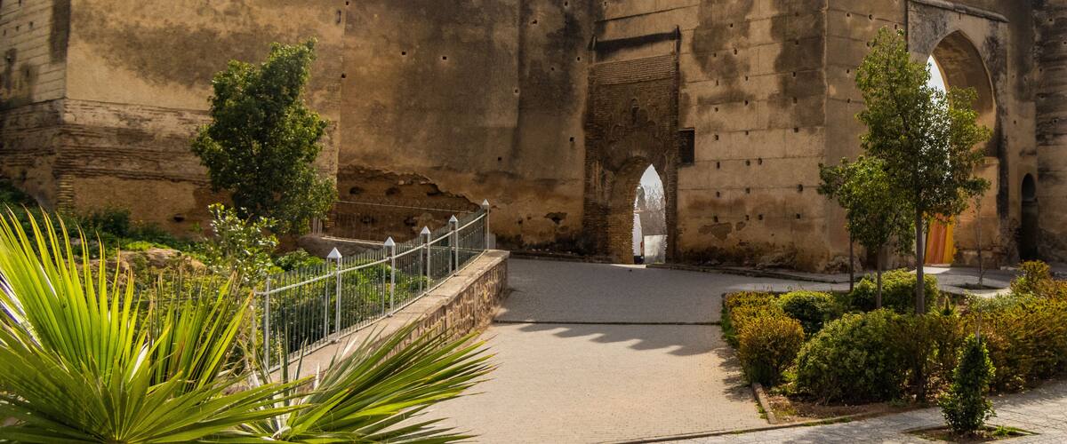 A historic stone wall with battlements and a gate.