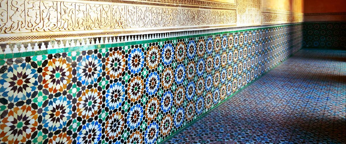 A detailed mosaic wall with geometric patterns and Arabic calligraphy.