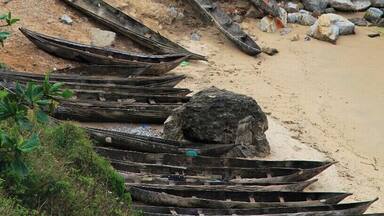 A beach with several wooden boats and a small house.