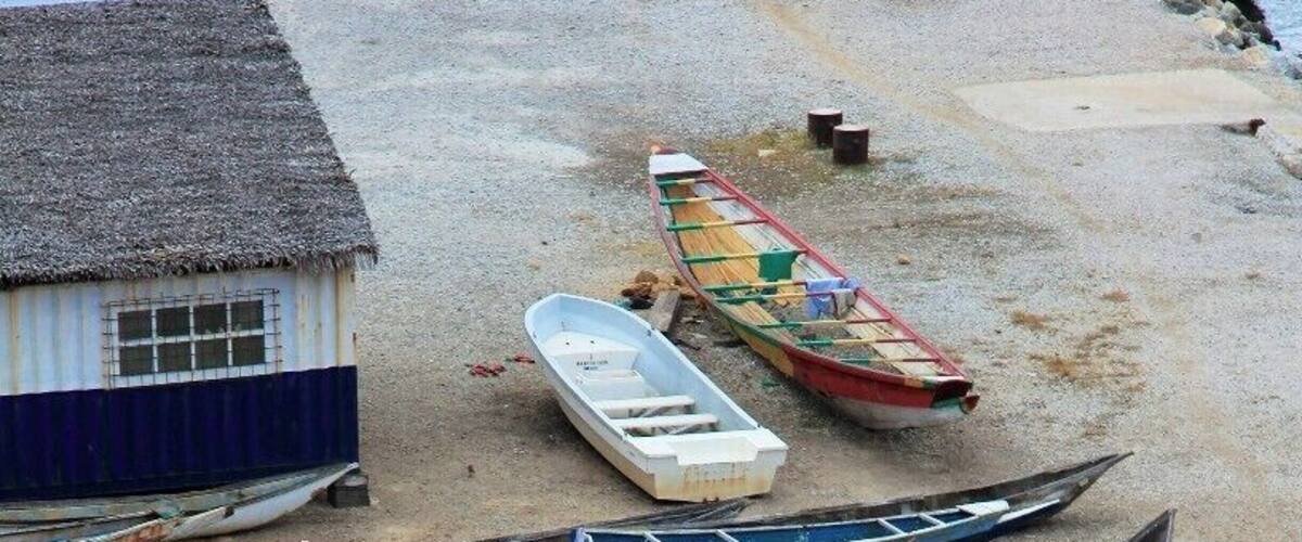 A beach with several wooden boats and a small house.