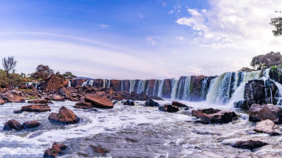A river with large rocks and a waterfall.