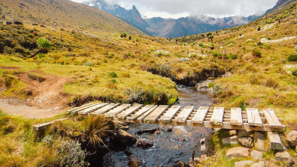 A wooden bridge on a fresh water river in the wild at Naro Moru route in Mount Kenya