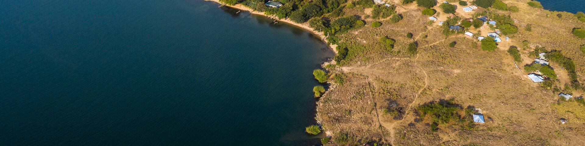 Aerial view of the island's beige and green landscape gently meets the endless blue waters of Lake Victoria, Takawiri Island, Homa Bay, Kenya.