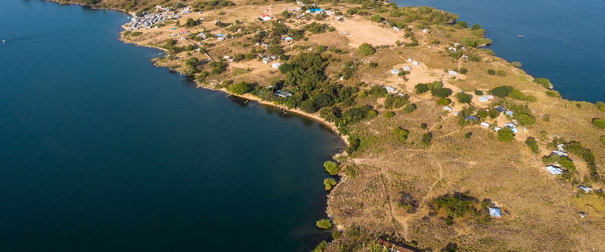 An aerial view of a coastal island with scattered houses and a lighthouse in the distance.