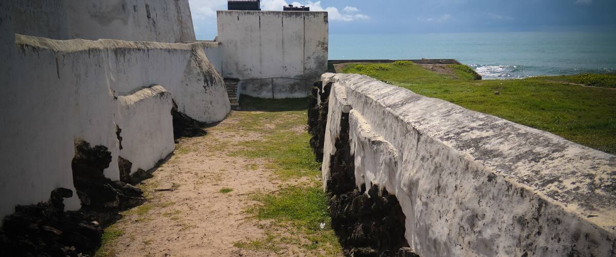 A coastal fortification with a dirt path leading to a grassy area overlooking the sea.