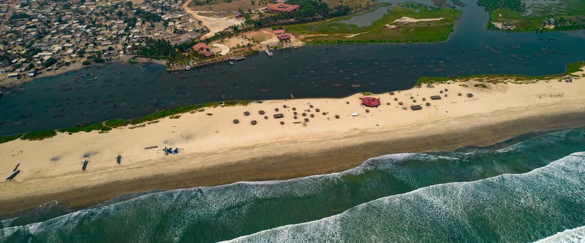 An aerial view of a coastal town with a beach, boats, and a river.
