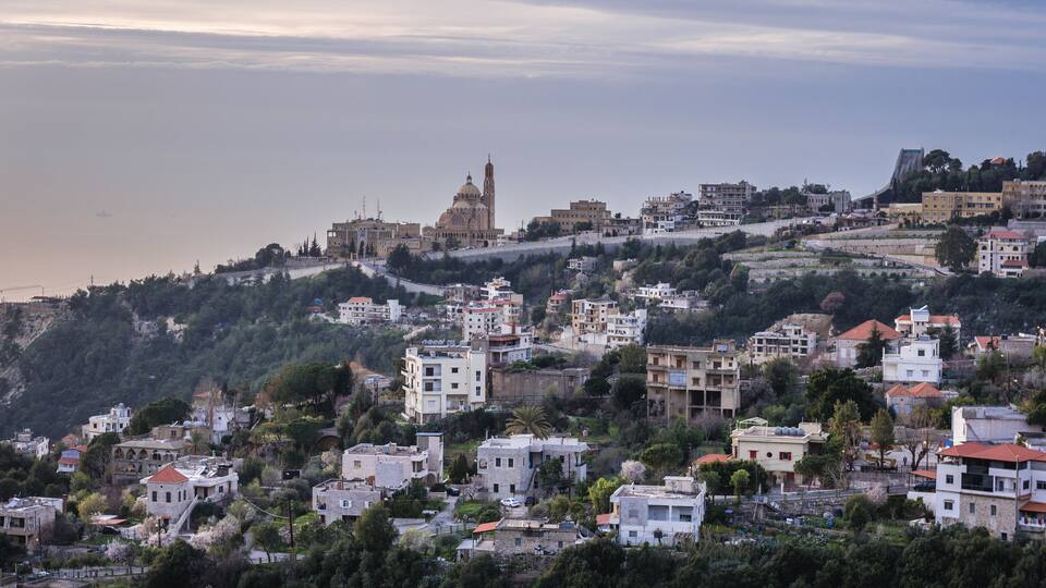 A coastal town with a prominent church, residential buildings, and a hilly landscape.