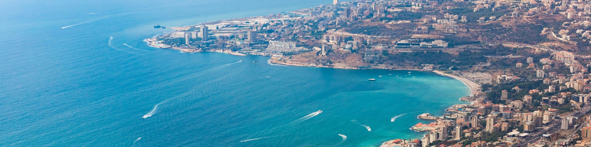 Un paisaje urbano costero con una playa destacada, edificios urbanos densos y un mar azul cristalino.