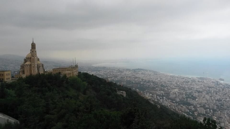 A cityscape with a prominent church on a hill and a view of the coastline.