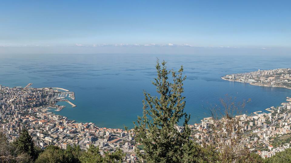 A coastal city with a bay, dense urban area, and a distant mountain range.