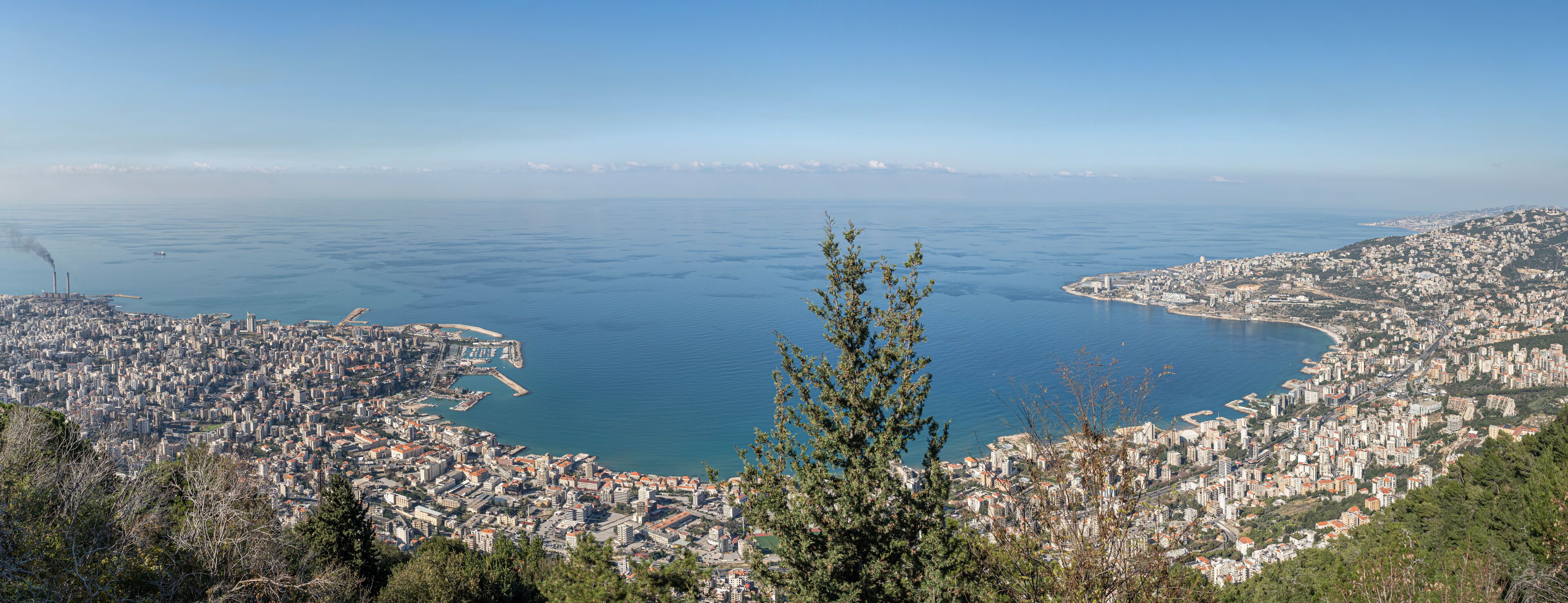 A coastal city with a bay, dense urban area, and a distant mountain range.