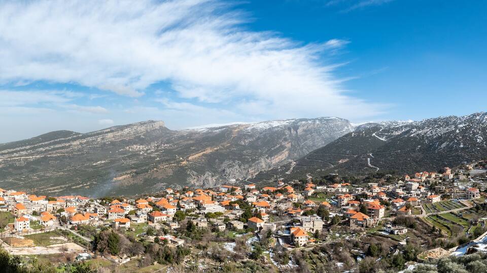 A town nestled in a valley with snow-capped mountains in the background.