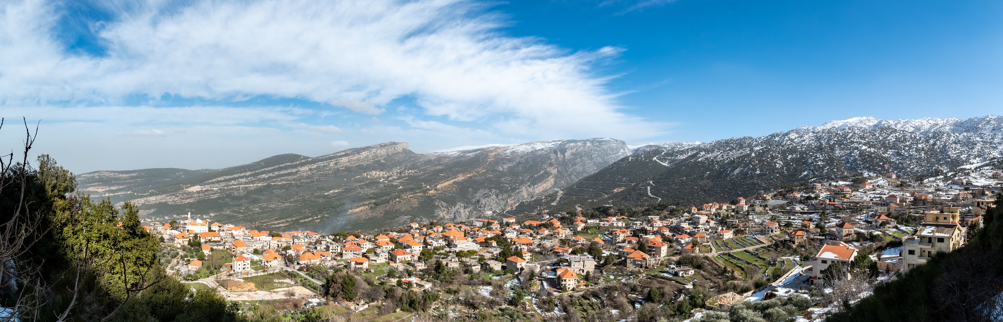 A town nestled in a valley with snow-capped mountains in the background.