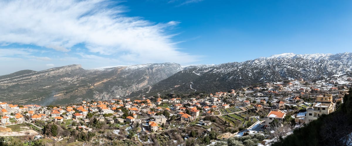A town nestled in a valley with snow-capped mountains in the background.