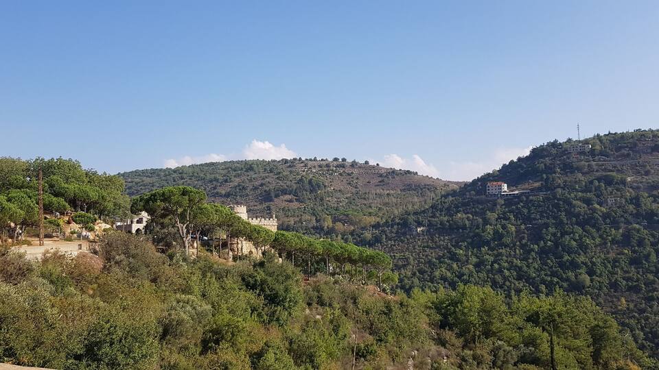 A mountainous landscape with scattered buildings and dense greenery.