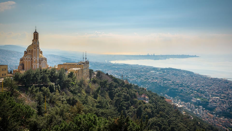 A coastal cityscape with a prominent church on a hill, dense urban area, and a body of water in the distance.