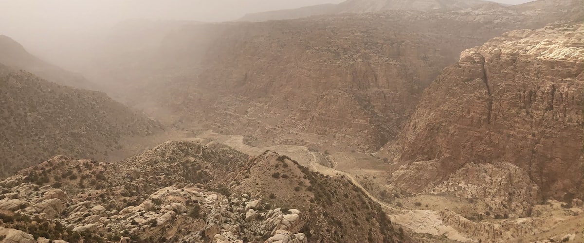 A rugged canyon landscape with steep cliffs and a winding river.