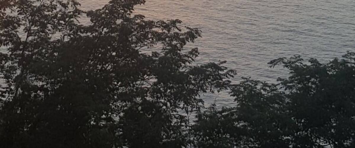 A sunset over a calm sea with a few clouds in the sky.