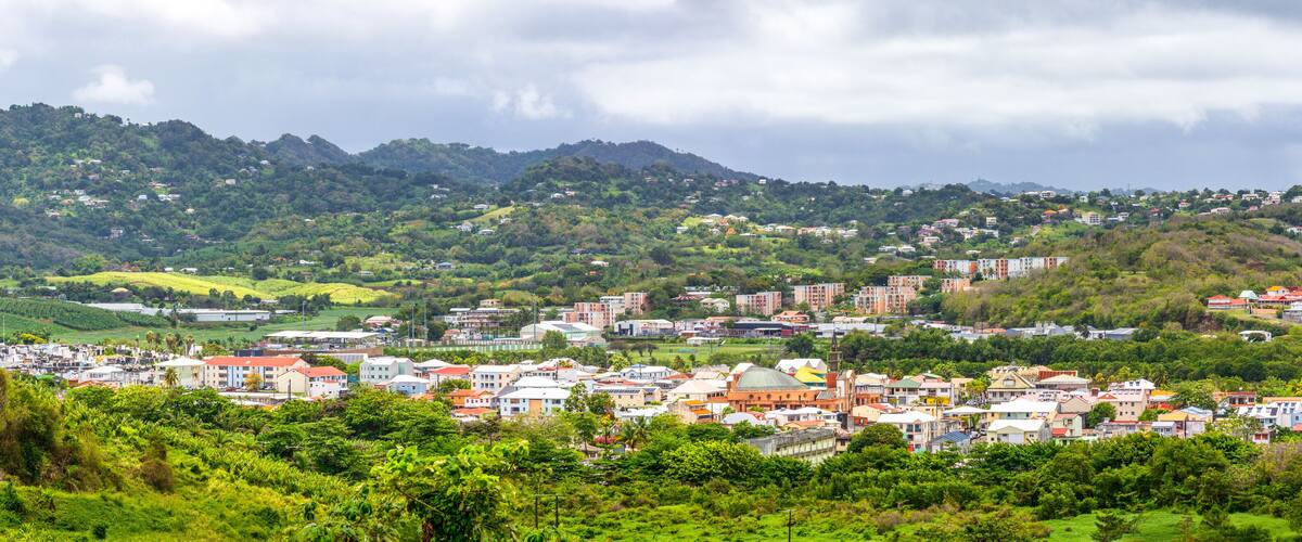 A town nestled in a valley with lush greenery and hills in the background.