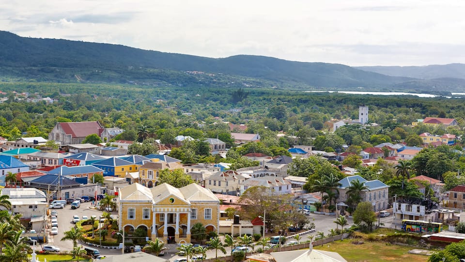 A coastal town with colorful buildings, a prominent yellow structure, and a church on a hill.