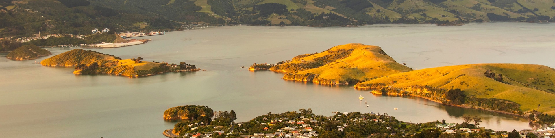 Eine Küstenlandschaft mit sanften Hügeln, einer kleinen Stadt und einem Gewässer.