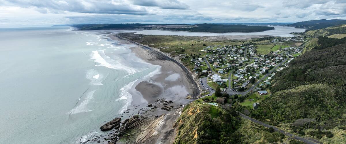 A coastal town with a beach, houses, and rolling hills.