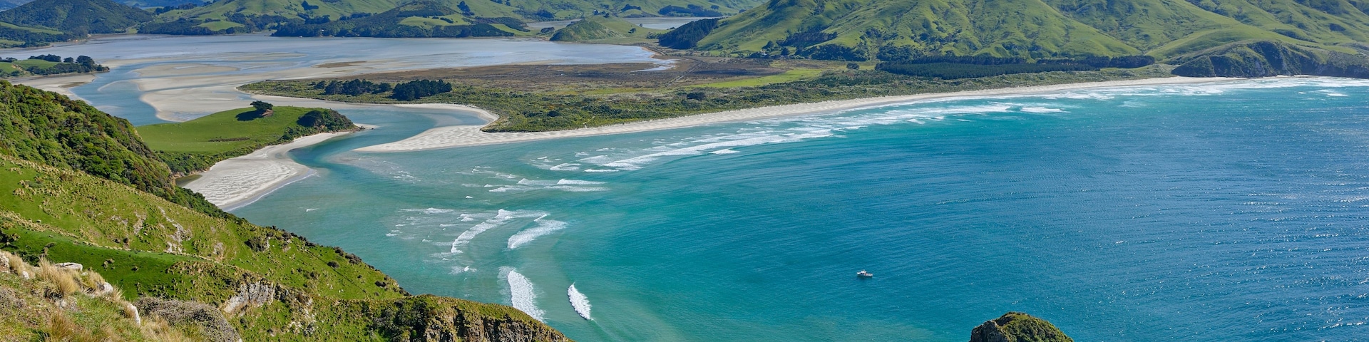 Paisagem costeira com colinas verdes, uma baía e mar azul cristalino.
