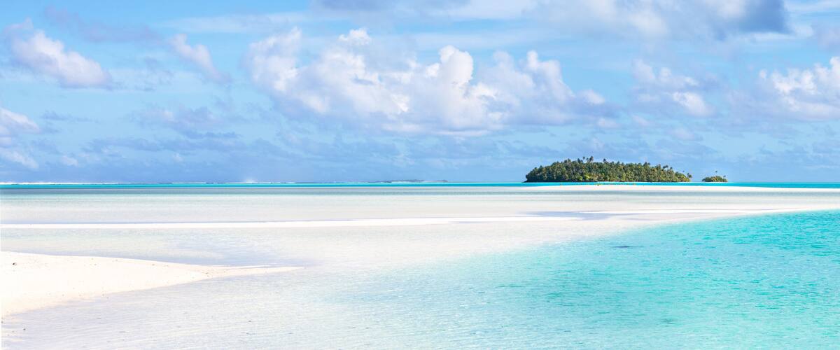 A tropical island surrounded by turquoise waters and a clear sky.
