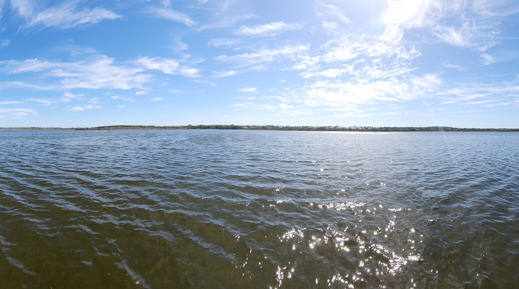 A calm lake with a forested shoreline and a clear sky.