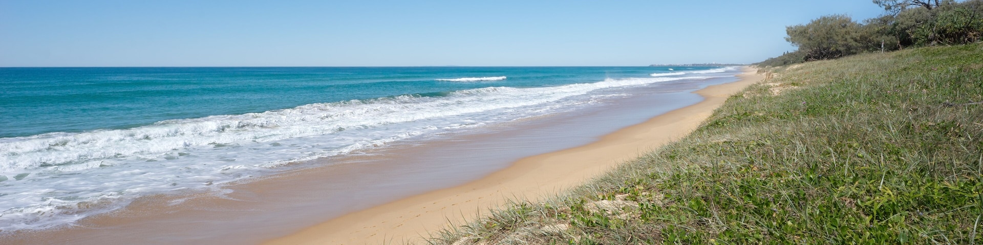 Ocean, breaking waves, shoreline and vegetated sand dunes at Buddina beach, Kawana on Queensland's Sunshine Coast.