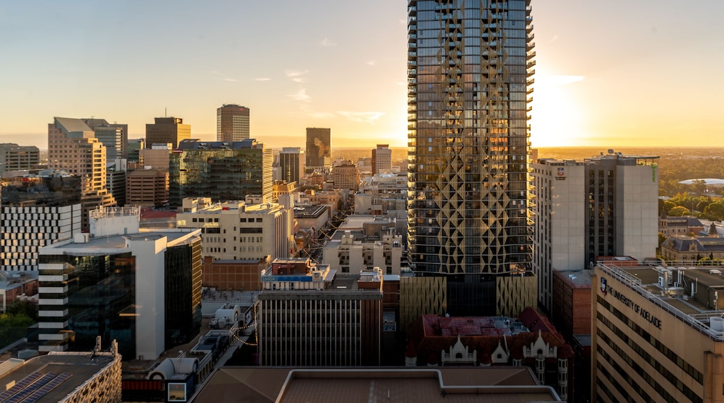 A cityscape with a prominent modern high-rise building, surrounded by other buildings and a clear sky.