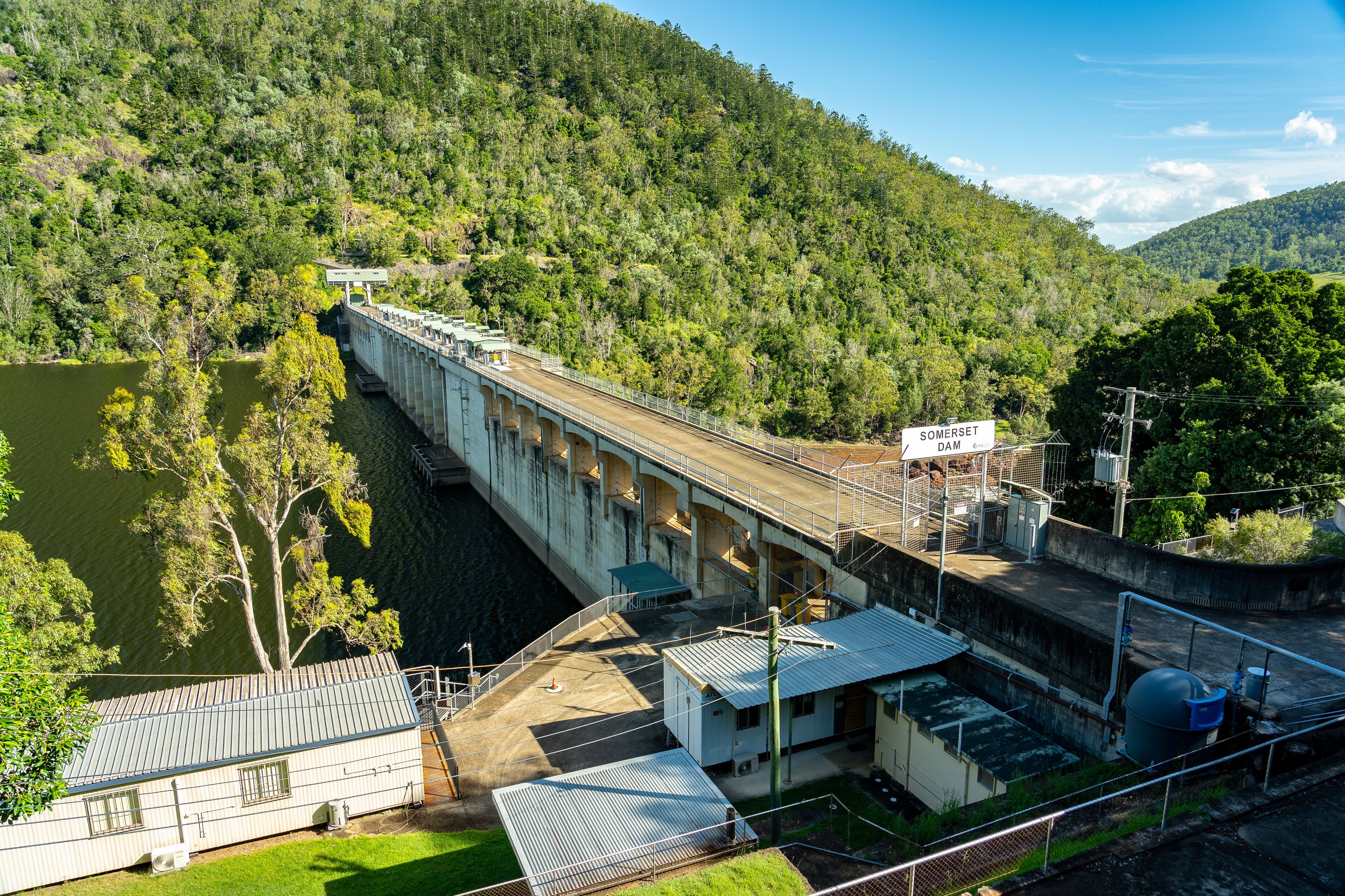 Una presa con un puente, rodeada de colinas boscosas.