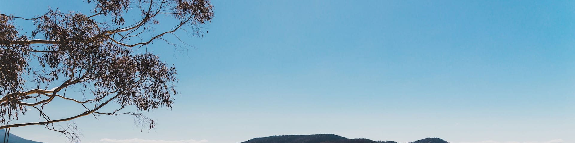 A beach with clear water, sandy shore, and distant hills.