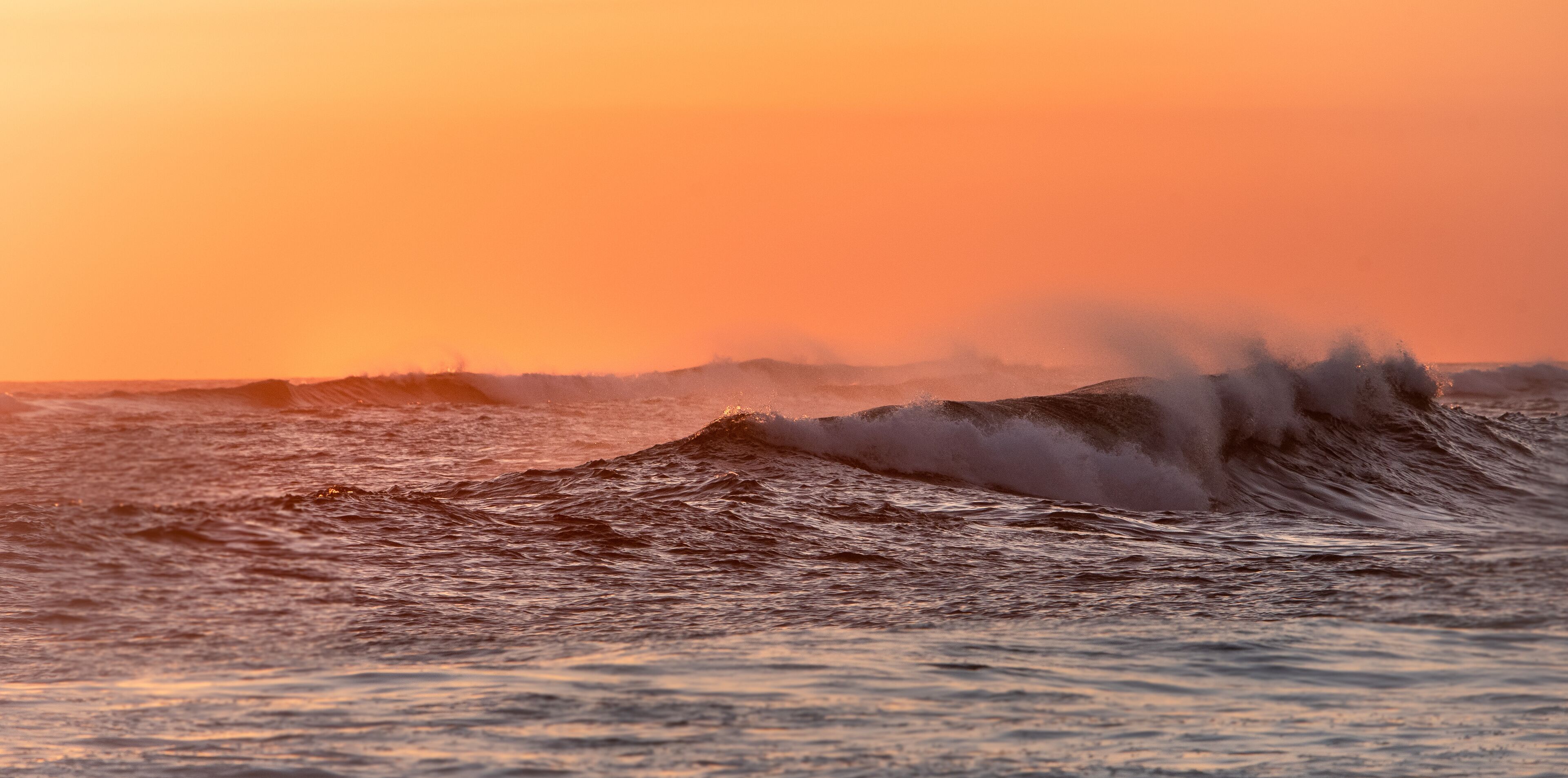 waves breaking at sunset creating spray