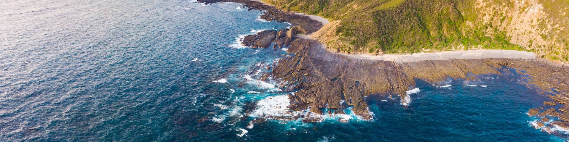 A coastal landscape with rocky cliffs and a winding road along the coastline.
