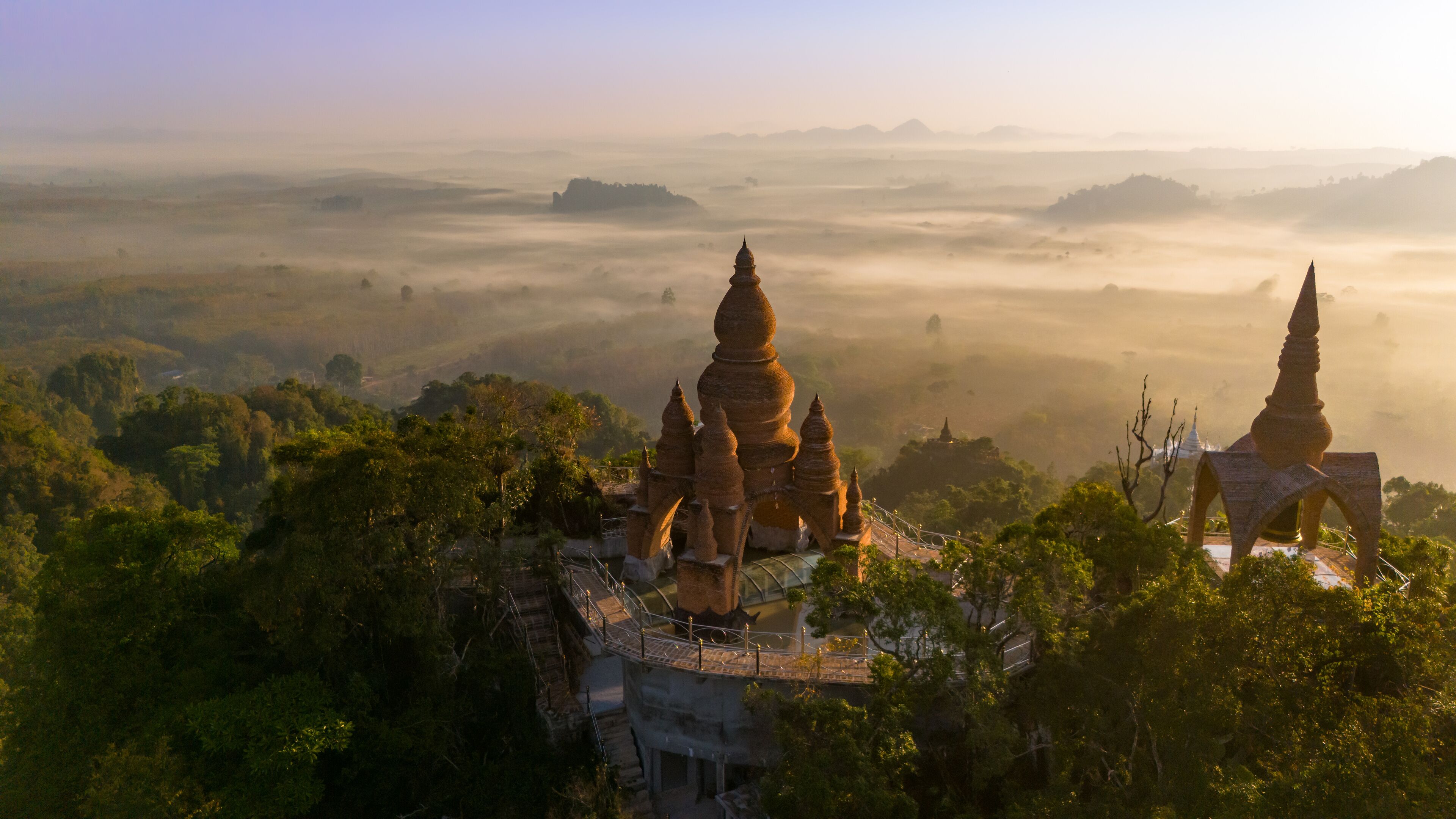 Beautiful sunrise with pagodas on the top of cliff, morning mist at Khao Na Nai Luang Dharma Park, Surat Thani province, Thailand