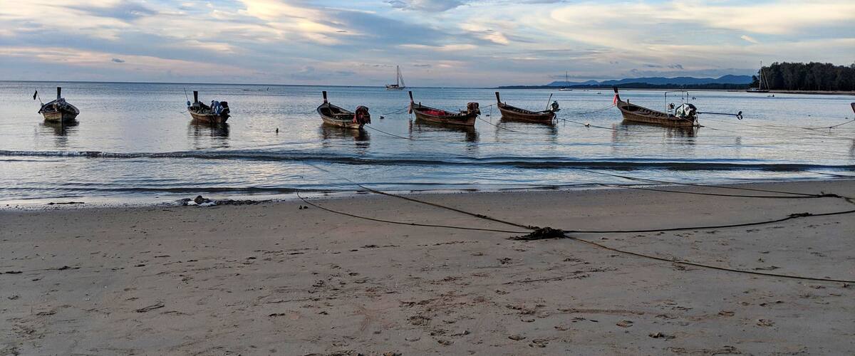 A beach with several boats anchored in the water.