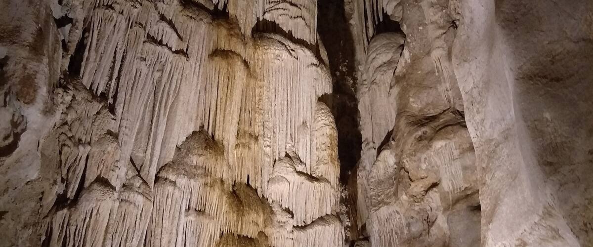 A cave with stalactites hanging from the ceiling and stalagmites rising from the ground.