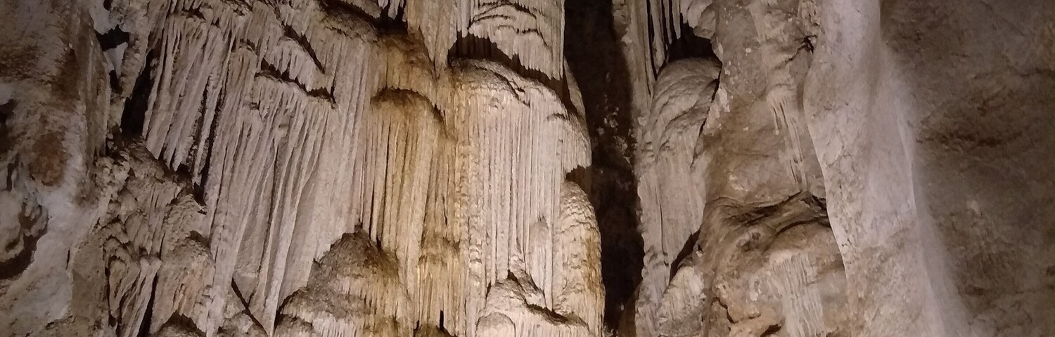 A cave with stalactites hanging from the ceiling and stalagmites rising from the ground.