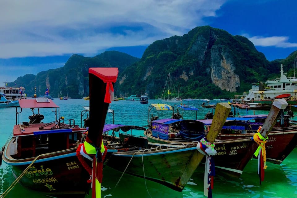 A harbor with boats docked, surrounded by green cliffs and a clear sky.