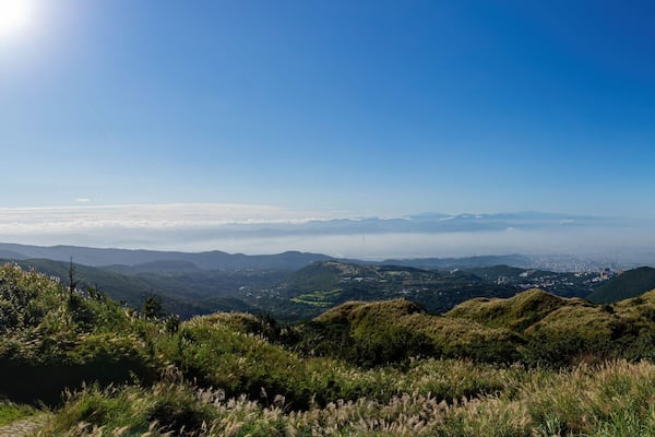 Un paysage montagneux, avec un ciel dégagé et une vue lointaine sur la ville.