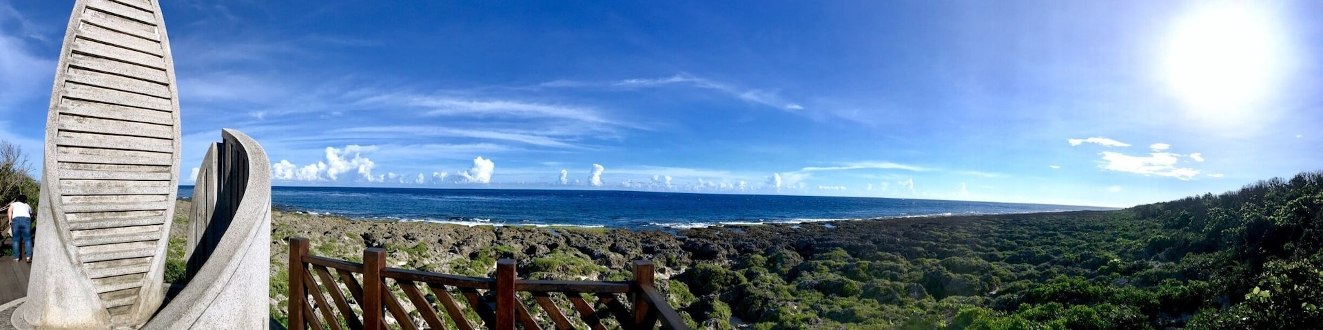 Paisagem costeira com estrutura de madeira e vista para o oceano.