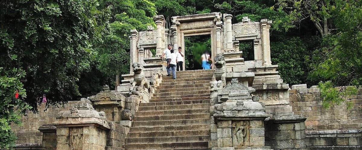 A stone staircase leading to a temple entrance surrounded by lush greenery.