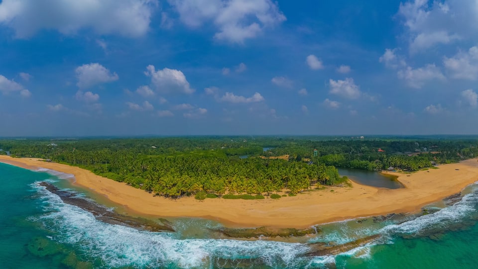 A tropical island with a sandy beach, dense palm trees, and turquoise waters.