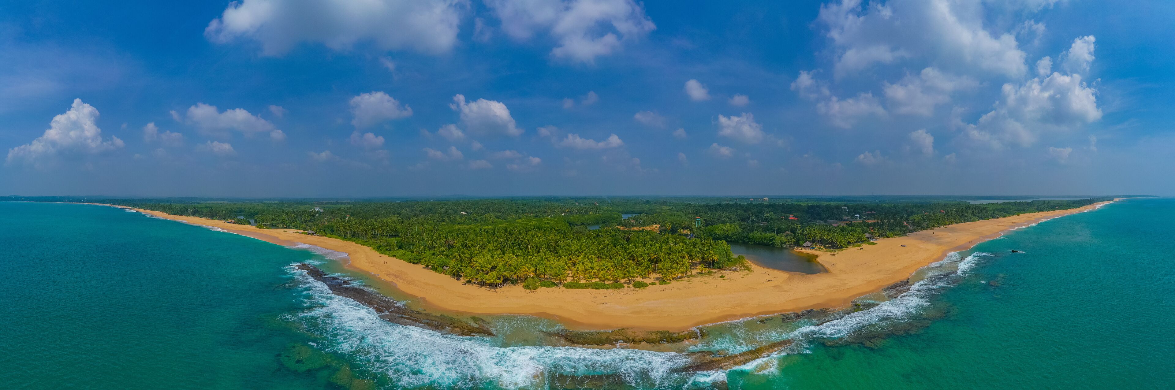 A tropical island with a sandy beach, dense palm trees, and turquoise waters.