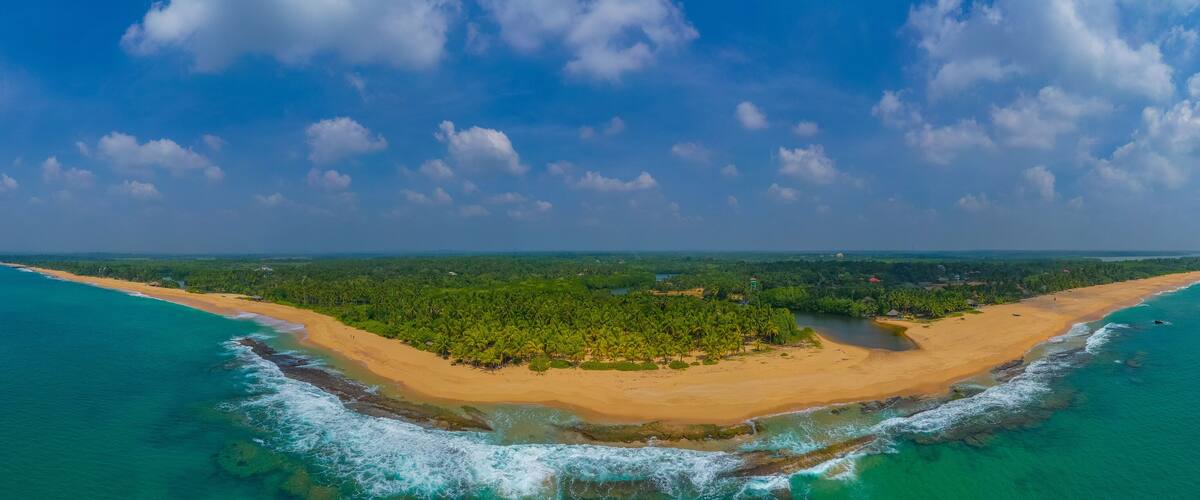 A tropical island with a sandy beach, dense palm trees, and turquoise waters.