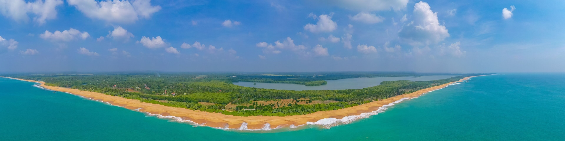 Un paisaje costero con una playa arenosa, aguas turquesas y una isla cubierta de bosque.